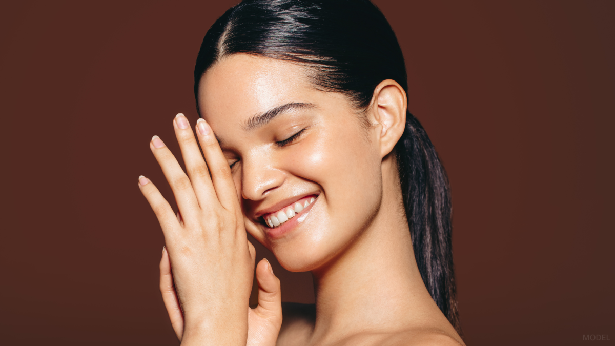 Woman with a beautiful nose smiling and touching her face (model)