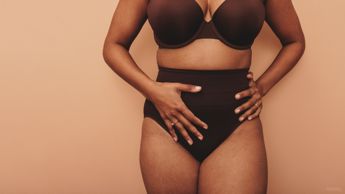 Woman wearing a bra and underwear with her hands on her stomach (model)